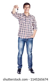 Full Body Portrait Of Smiling Young Man Showing New House Key, Other Hand In Pocket Wearing Metal Frame Glasses, Checkered Shirt, Blue Jeans And Black Shoes Isolated On White Background