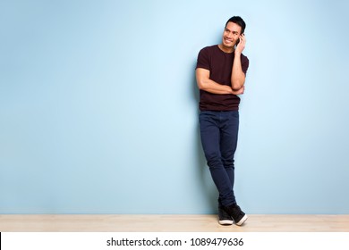 Full Body Portrait Of Stylish Mature Asian Man Standing By Blue Wall And Making A Phone Call