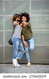 Full Body Portrait Two Happy Young Black Women Taking Selfie With Cellphones 