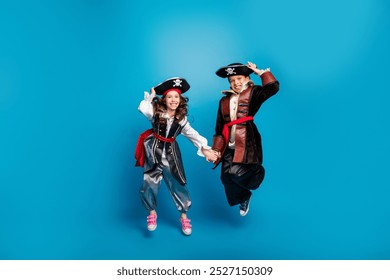 Full body portrait of two little kids hold arms jump halloween pirate costume isolated on blue color background - Powered by Shutterstock