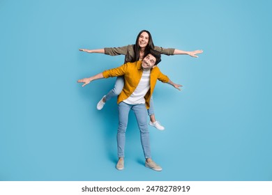 Full body portrait of two young people piggyback arrms wings wear shirt isolated on blue color background - Powered by Shutterstock