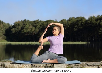 Full Body Portrait Of A Woman Doing Yoga Advanced Pose In A Lake On Summer