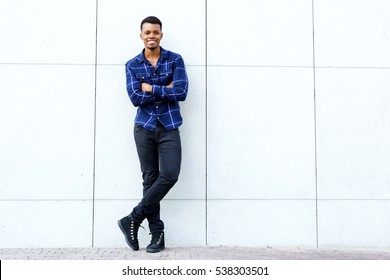 Full Body Portrait Of Young African American Man Smiling Against Wall With Arms Crossed