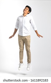 Full body portrait of young Asian man in white casual shirt pose like standing in the air with impress  happiness and sweetly close eyes. Studio shot on white background. 