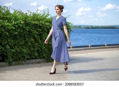 Full body portrait of a young beautiful brunette woman walking in summer park