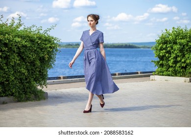 Full body portrait of a young beautiful brunette woman walking in summer park