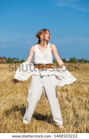 Full body portrait young beautiful blonde woman in a beige suit posing against the background of a mowed wheat field