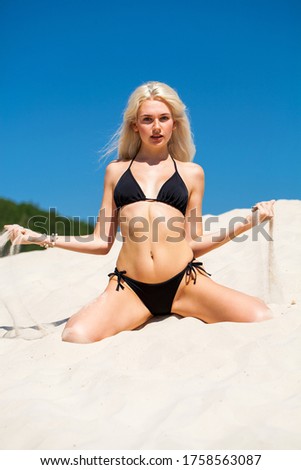 Full body portrait of a young beautiful blonde girl in black bikini
