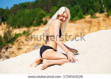 Full body portrait of a young beautiful blonde girl in black bikini
