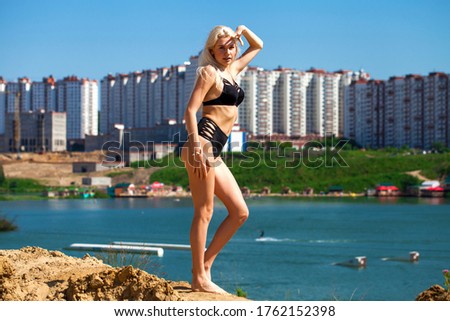 Full body portrait of a young beautiful blonde girl in black bikini