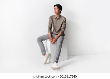 full body Portrait young man in shirt, gay pants sitting cube in studio - Powered by Shutterstock