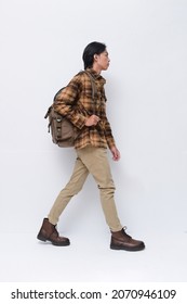 Full Body Portrait Of Young Man Wearing Plaid With Khaki Pants With Backpack, Walking On White Background