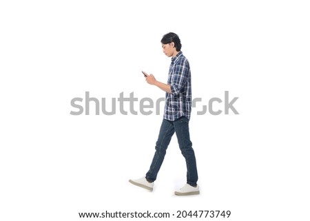 Full body portrait of young man with jeans using cellphone in studio isolated on white background

