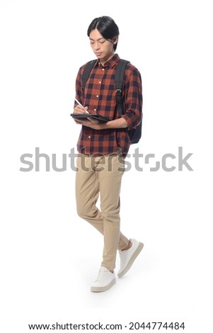 Full body portrait of young man with backpack holding using digital tablet in studio isolated on white background

