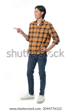 Full body portrait of young man with jeans with finger to side in studio isolated on white background

