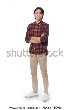 Full body portrait of young man wearing plaid with arms crossed posing on white background,