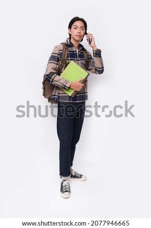 full body portrait of young man wearing plaid jacket, hoodie with jeans and uses a mobile phone on white background