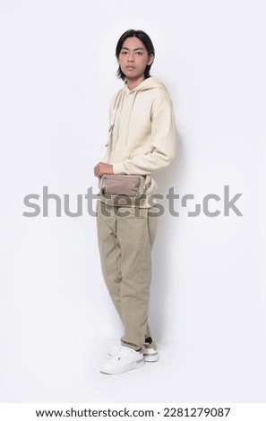 Full body portrait of young man wearing hoodie with handbag posing on white background,