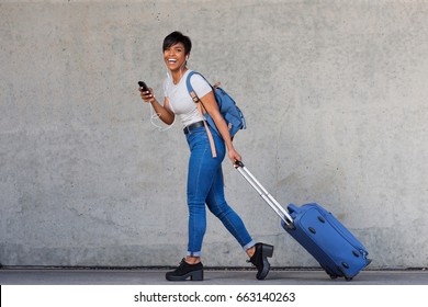 Full Body Portrait Of Young Woman Walking With Travel Bag And Mobile Phone