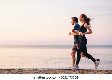Ganzkörperprofil Paar junge zwei Freunde starke sportliche Sportlerin Mann 20s in Sportbekleidung Warmaufwärmen Training laufen auf Sand-Meer-Strand Außenjoggen am Meer im Sommer Tag Morgen am Meer