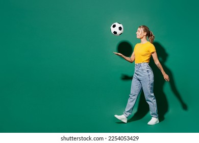 Full body profile happy young woman fan wear yellow t-shirt cheer up support football sport team hold in hand soccer ball watch tv live stream walk go throw up ball isolated on dark green background - Powered by Shutterstock