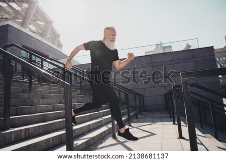 Full body profile photo of aged grey hair sporty man show run wear black t-shirt shorts footwear outside in stadium.