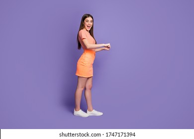 Full body profile photo of attractive lady addicted shopper leading rolling imaginary store trolley wear orange striped t-shirt jeans mini skirt isolated pastel purple color background