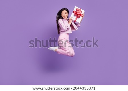 Full body profile photo of cool millennial brunette lady jump hold present wear jacket jeans sneakers isolated on violet background