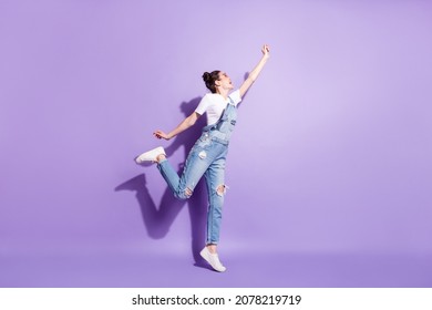 Full body profile photo of funky brown hair lady jump catch wear spectacles t-shirt overall isolated on violet background