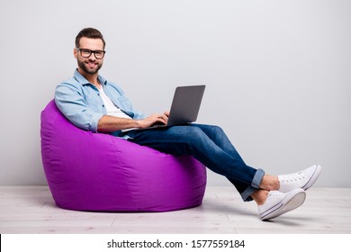 Full Body Profile Photo Of Funny Guy Holding Notebook Browsing Chatting Colleagues Sitting Comfy Soft Armchair Wear Specs Casual Denim Outfit Isolated Grey Color Background