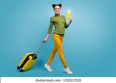 Full Body Profile Photo Of Funny Pretty Lady Hold Tickets Passport Cheap Flight Rolling Suitcase Walk Airport Wear Green Turtleneck Yellow Pants Footwear Isolated Blue Color Background