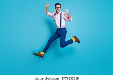 Full Body Profile Photo Of Handsome Man Jump High Up Running Competition Work Worker Raise Fists First Place Winner Wear Specs Shirt Suspenders Pants Boots Isolated Blue Color Background
