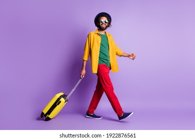 Full body profile photo of handsome cheerful dark skin person walking carry bag isolated on violet color background