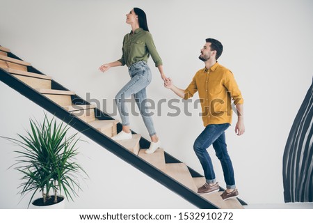 Full body profile photo of handsome guy and his pretty lady leading macho to bedroom going up stairs in modern interior hotel room indoors wear casual clothes
