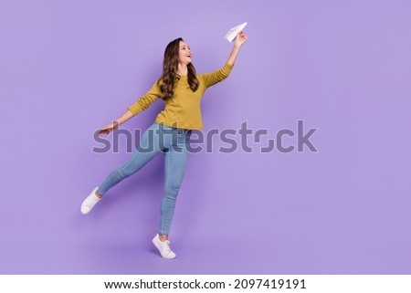Full body profile photo of pretty positive person hand hold paper plane isolated on purple color background