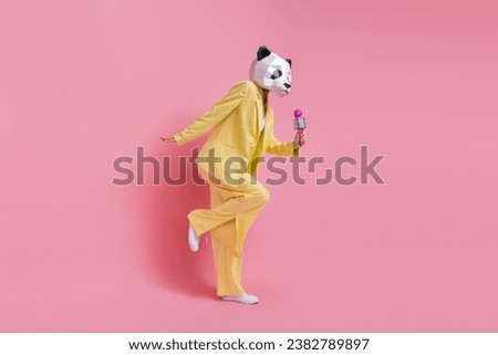 Full body profile portrait of charismatic weird 3d panda mask lady hold mic sing dance isolated on pink color background