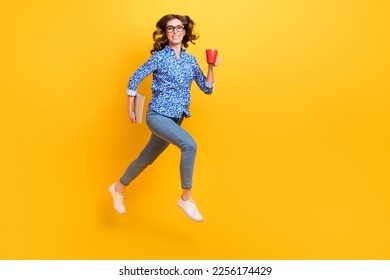 Full body profile portrait of excited active lady hold netbook coffee mug jumping isolated on yellow color background - Shutterstock ID 2256174429