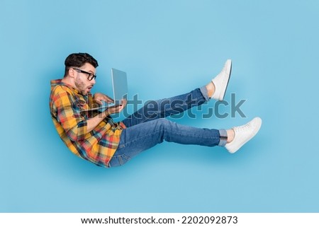 Full body profile portrait of falling flying person use wireless netbook isolated on blue color background