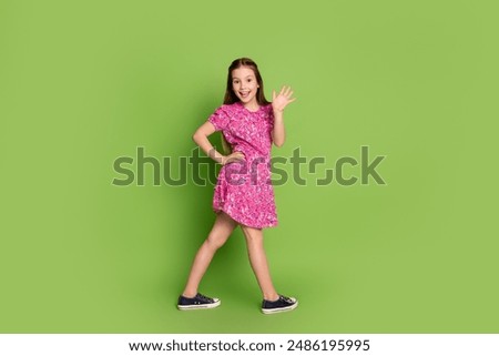 Full body profile portrait of lovely schoolgirl arm wave hi empty space wear pink dress isolated on green color background