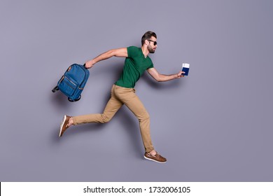 Full body profile side photo of serious guy jump run dont want miss check in passing board hold visa tickets bag backpack wear green trousers isolated over gray color background