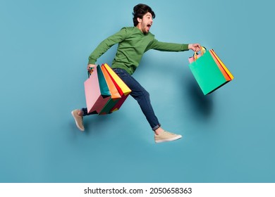 Full body profile side photo of crazy smiling guy running shopaholic black friday isolated on blue color background