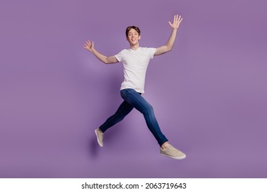 Full body profile side photo of young man good mood go walk run jump isolated on violet color background - Shutterstock ID 2063719643
