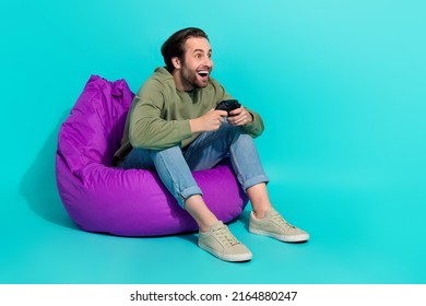Full Body Profile Side Photo Of Young Man Sit Violet Beanbag Race Speed Competition Isolated Over Turquoise Color Background