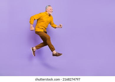 Full body profile side photo of senior man run hurry fast motion look empty space isolated over purple color background - Powered by Shutterstock