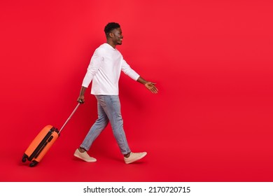 Full Body Profile Side Photo Of Positive Man Go In Airport With Baggage Summer Vacation Isolated On Red Color Background