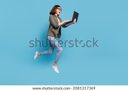 Full body profile side photo of computer nerd lady jump use device chatting wear shirt denim jeans isolated over blue color background
