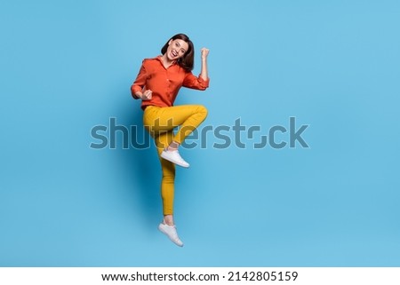 Full body profile side photo of young excited girl celebrate success fists hands triumph jump isolated over blue color background