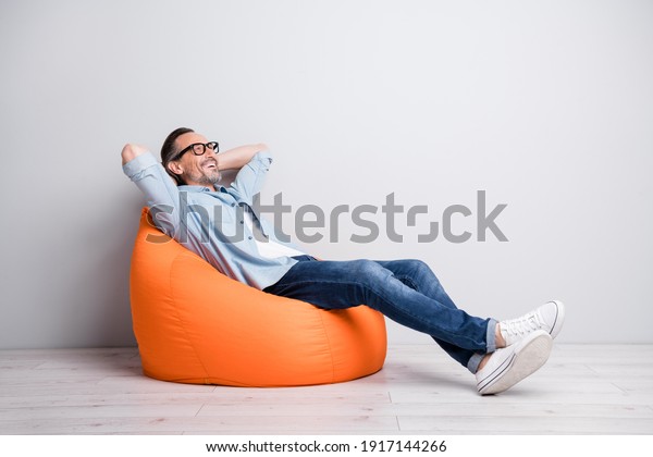 Full body profile side photo of man happy\
positive smile sit bag rest relax look empty space isolated over\
grey color background