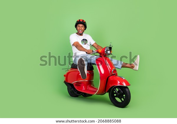 Full body\
profile side photo of young african man drive motor bike vehicle\
isolated over green color\
background