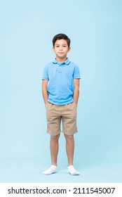 Full Body Self Assured Child In Casual Clothes And Socks Holding Hands In Pockets And Looking At Camera Against Blue Background